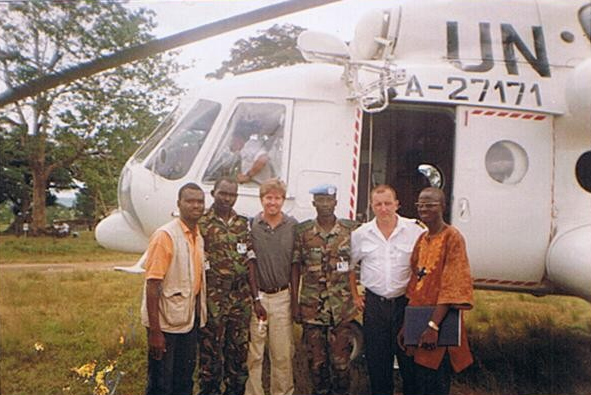 Peace and human rights mission members standing in front of helicopter